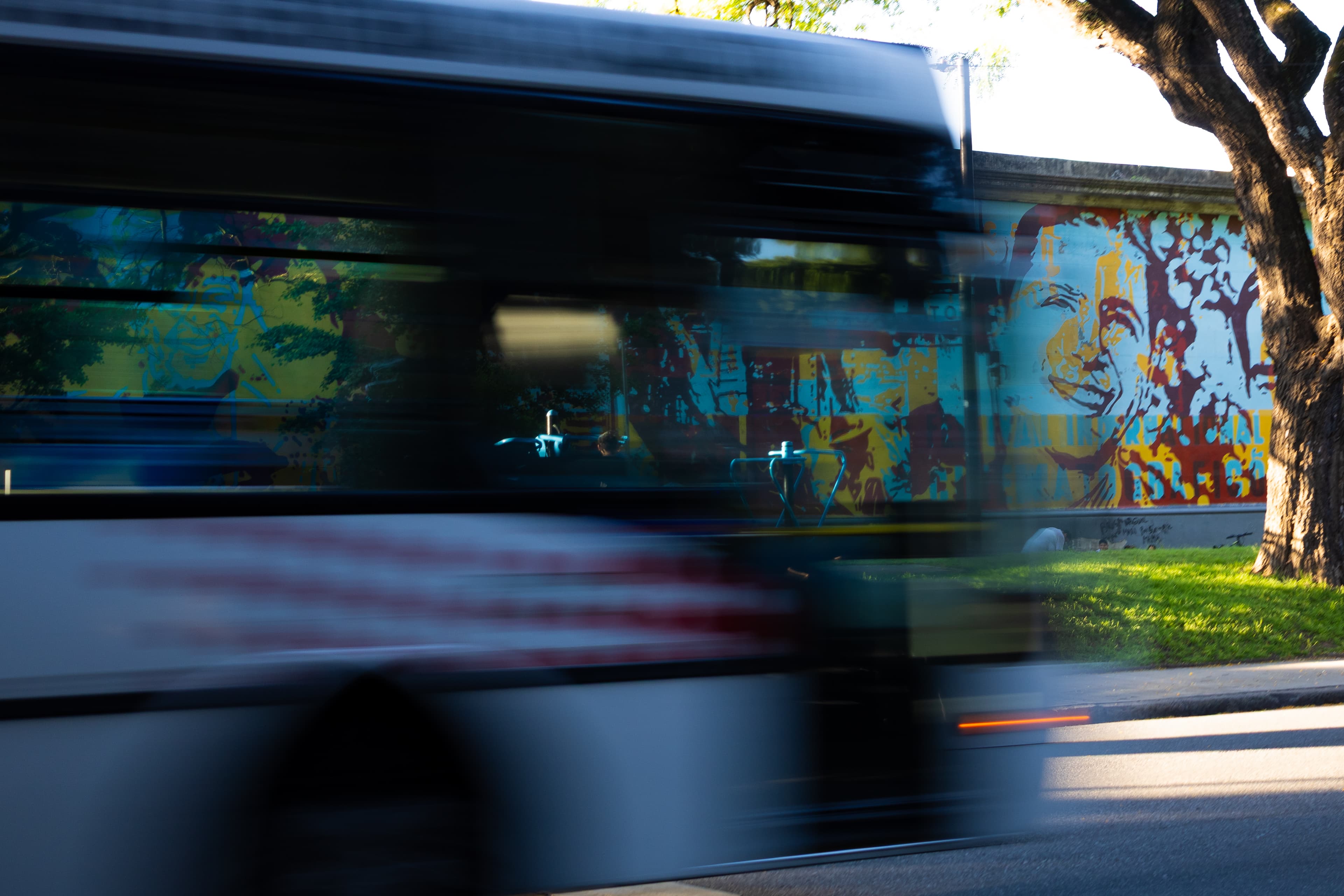 Mural faces behind a passing bus