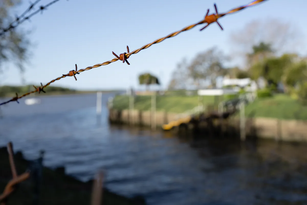 Barbed wire with river and small dock off focus in the background