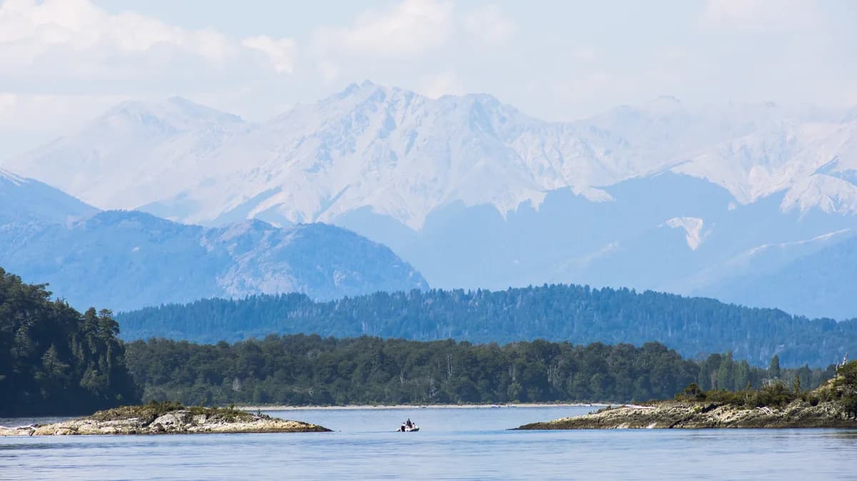 Small inflatable boat on a lake with huge mountains in the background