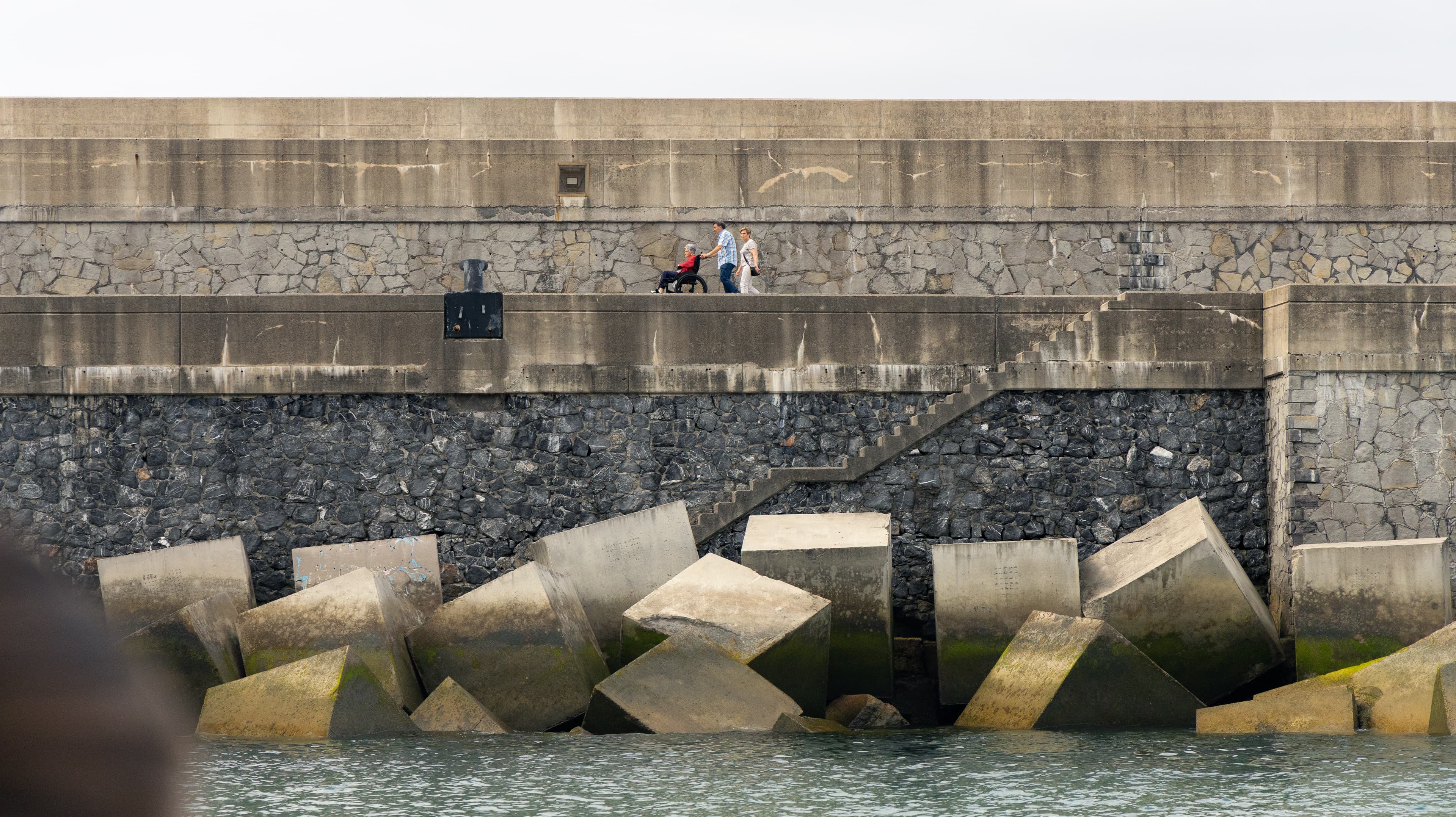 People stroll along a concrete breakwater