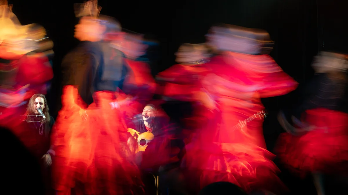 Trails of colorful flamenco dancers with musicians in between during a Sevillana