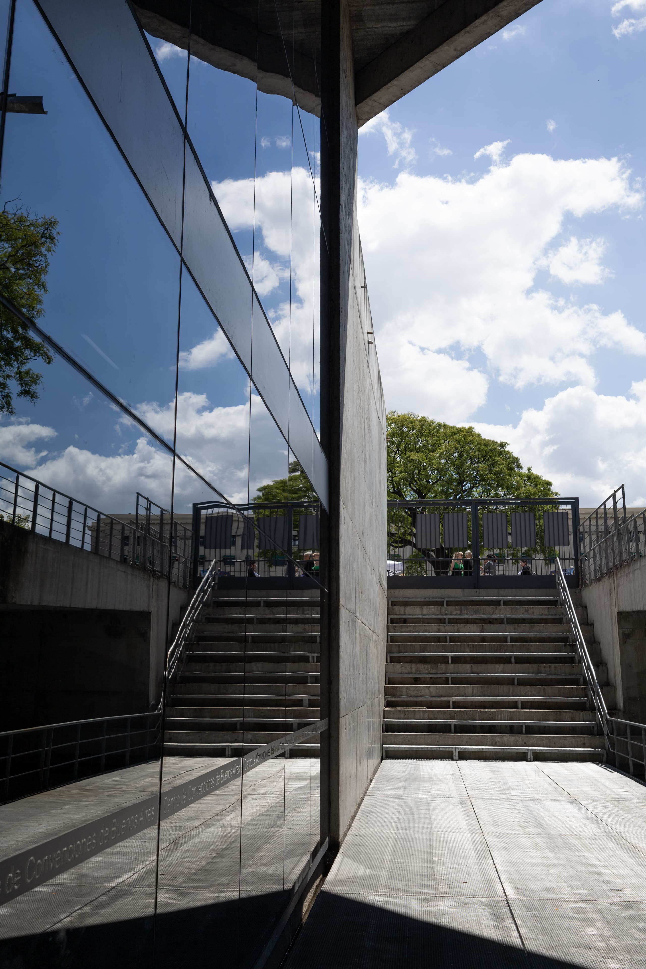 Symmetrical reflecion of stairs and sky on a neo-brutalist building's windows