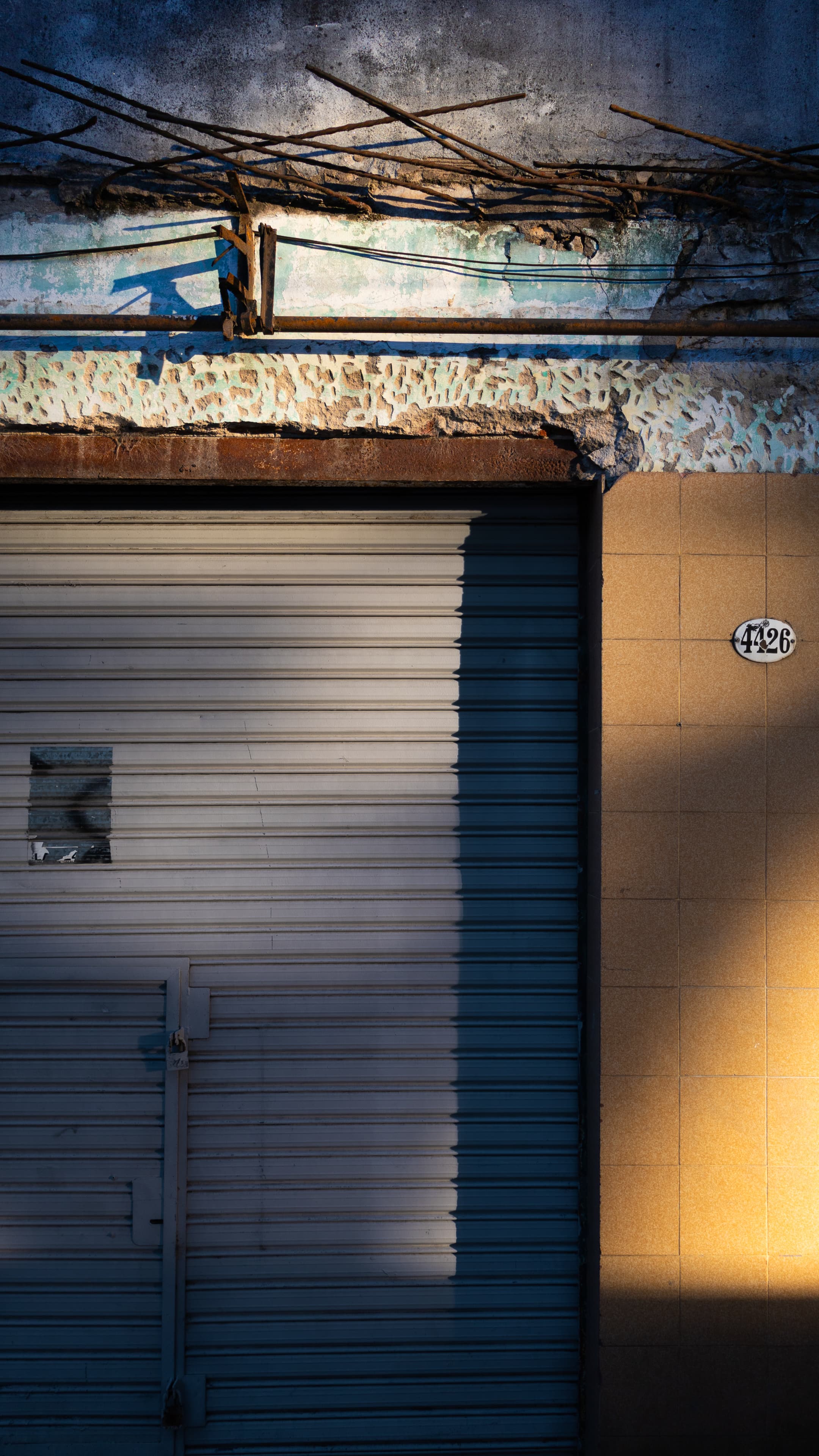 Iron, metal curtain, ceramic tiles and old paint on cement on a façade