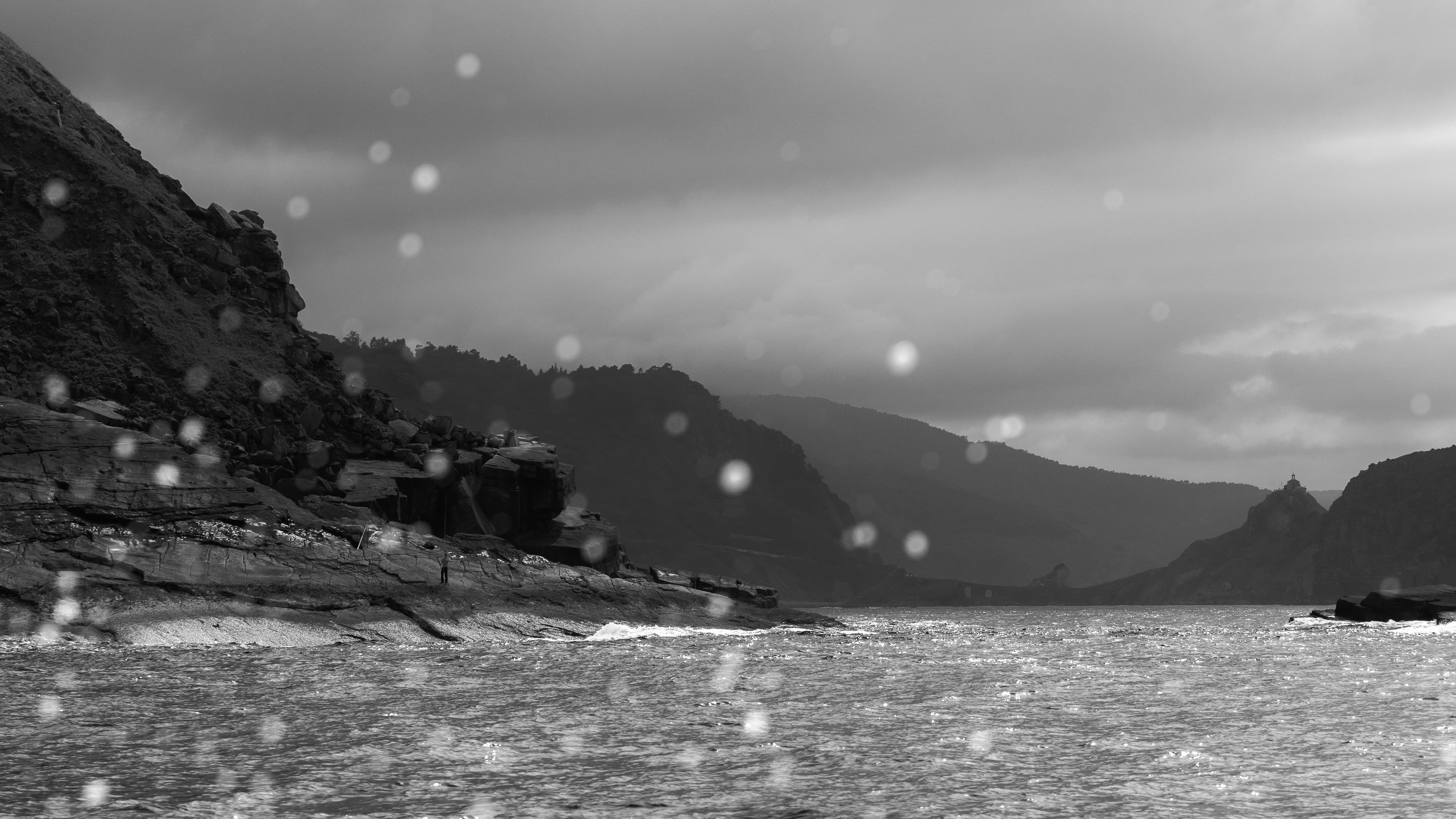 Black and white view of a dramatic coastline with cliffs fading into distant storm haze